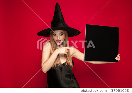 Young woman in hat as a witch on red background Young woman in hat as a witch on red background 57061068