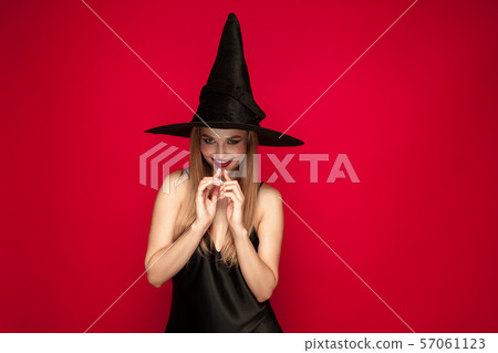 Young woman in hat as a witch on red background Young woman in hat as a witch on red background 57061123