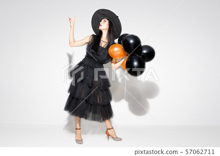 Young woman in hat and dress as a witch on white background 57062711