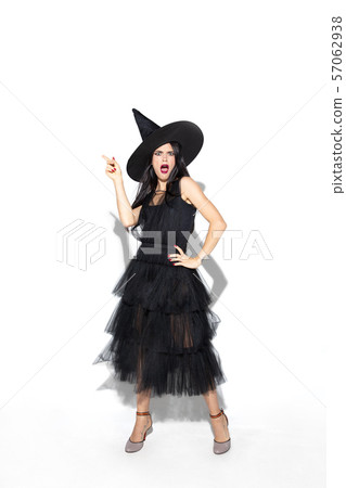 Young woman in hat and dress as a witch on white background 57062938
