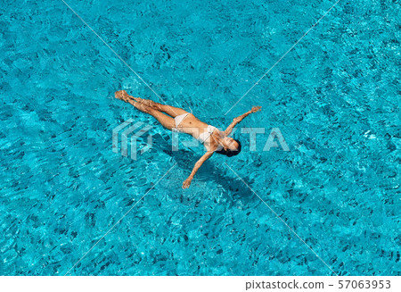 Top view of young slim woman in white bikini relax and floating in infinity swimming pool 57063953