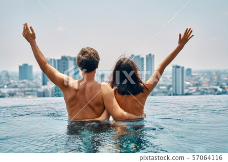 Young happy couple in love with arms up having fun in swimming pool Young happy couple in love with arms up having fun in swimming pool 57064116