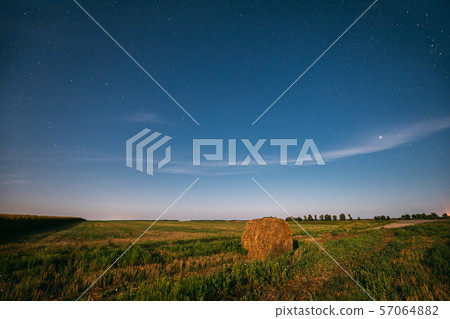 Natural Night Starry Sky Above Field Meadow With Hay Bale After Harvest. Glowing Stars Above Rural Natural Night Starry Sky Above Field Meadow With Hay Bale After Harvest. Glowing Stars Above Rural 57064882