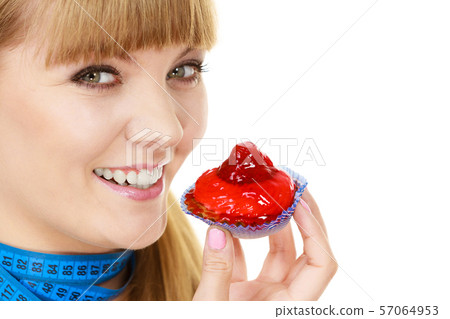 Woman holds cupcake trying to resist temptation 57064953