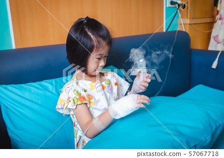 Sad asian child holds a mask vapor inhaler for treatment of asthma. Sad asian child holds a mask vapor inhaler for treatment of asthma. 57067718