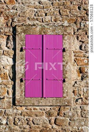 Old purple closed window in stone wall 57068128