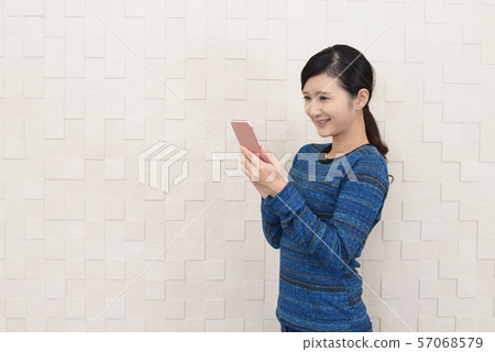 A smiling woman with a smartphone A smiling woman with a smartphone 57068579