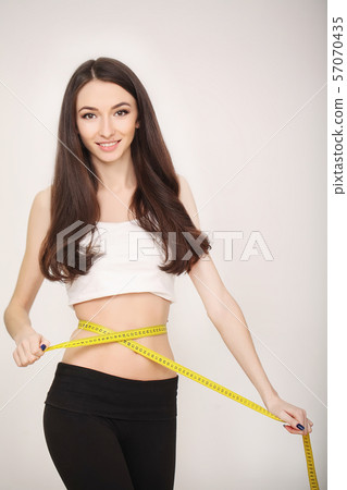 Diet. The girl taking measurements of her body, white background. 57070435