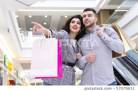 Consumerism concept. Woman showing man store in shopping mall Consumerism concept. Woman showing man store in shopping mall 57070631