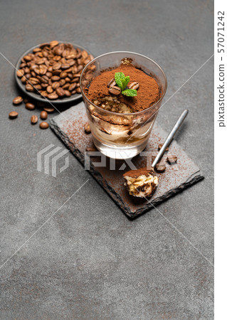 Portion of Classic tiramisu dessert in a glass cup on dark concrete background Portion of Classic tiramisu dessert in a glass cup on dark concrete background 57071242
