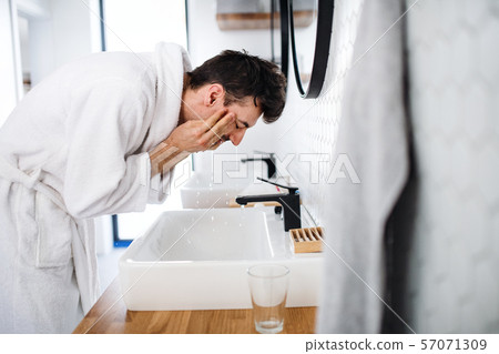 Young man washing face in the bathroom in the morning, daily routine. Young man washing face in the bathroom in the morning, daily routine. 57071309