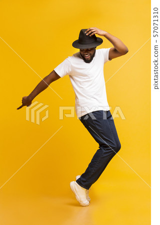 Young cheerful man dancing on tiptoes on yellow studio background Young cheerful man dancing on tiptoes on yellow studio background 57071310