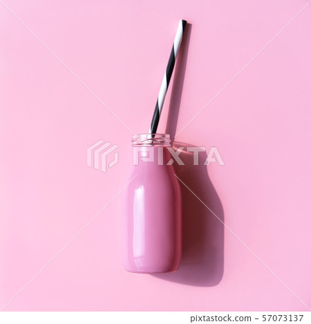 Pink bottle for a drink with a straw on the pink background. 57073137
