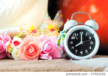 Small alarm clock with beautiful flowers on table 57081036