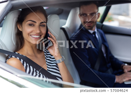 Wife speaking by phone while sitting near husband in car Wife speaking by phone while sitting near husband in car 57084624