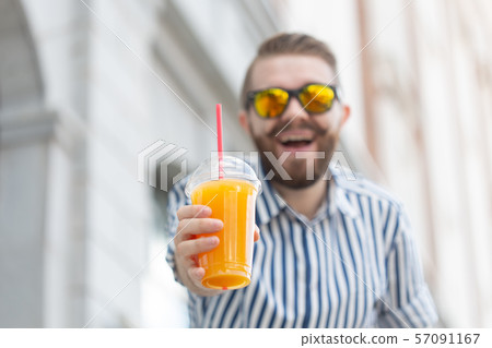 Portrait of a blurred stylish young hipster male with beard and mustache holding fresh orange juice Portrait of a blurred stylish young hipster male with beard and mustache holding fresh orange juice 57091167