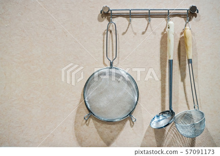 Kitchen cooking utensils on steel rack; steel spatulas etc against rustic wooden wall Kitchen cooking utensils on steel rack; steel spatulas etc against rustic wooden wall 57091173