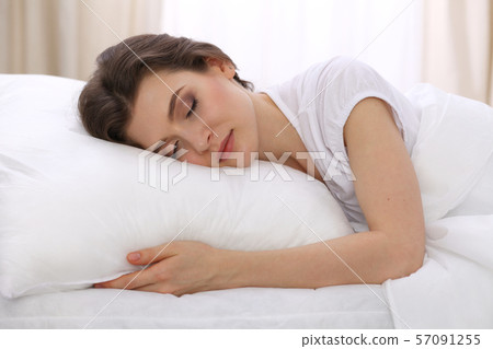 Beautiful young woman sleeping while lying in her bed. Concept of pleasant and rest reinstatement Beautiful young woman sleeping while lying in her bed. Concept of pleasant and rest reinstatement 57091255