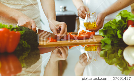 Closeup of human hands cooking in kitchen. Mother and daughter or two female friends cutting Closeup of human hands cooking in kitchen. Mother and daughter or two female friends cutting 57091437
