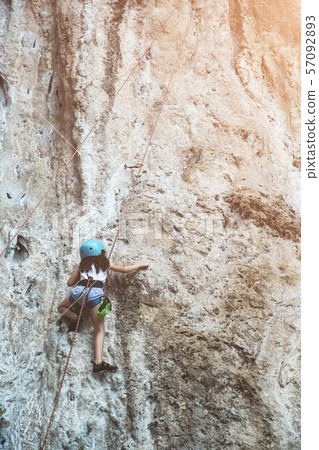 Little girl climbing a rock wall outdoor. Little girl climbing a rock wall outdoor. 57092893