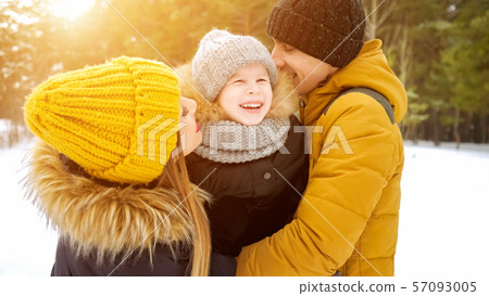 Mom and dad are cuddling and kissing their little son in winter park. 57093005