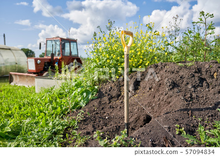 Shovel stuck in the ground against a compost pit Shovel stuck in the ground against a compost pit 57094834