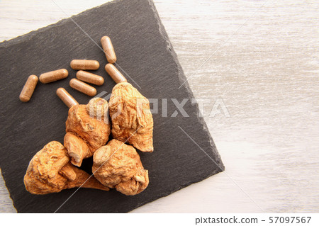 Maca capsules with dried maca on a stone dish 57097567