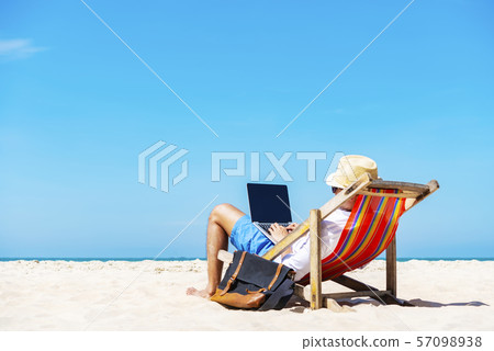 A man using laptop on the tropical beach on 57098938