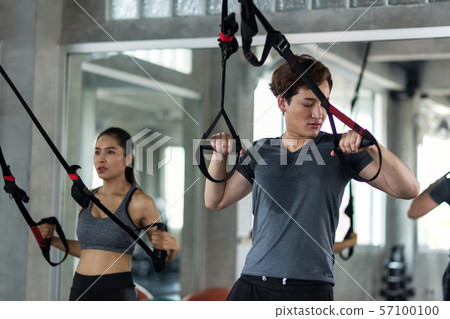 Happy couple exercise abdominal straps in gym Happy couple exercise abdominal straps in gym 57100100
