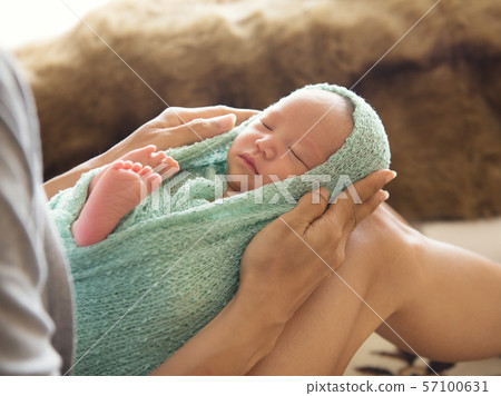 woman holding a newborn baby on her legs woman holding a newborn baby on her legs 57100631