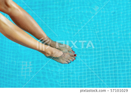 Female legs in the pool water. 57101029