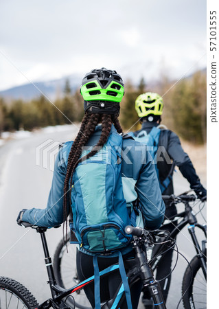 Rear view of two mountain bikers on road outdoors in winter. Rear view of two mountain bikers on road outdoors in winter. 57101555