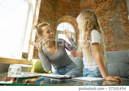 Teacher and little girl, or mom and daughter. Homeschooling concept Teacher and little girl, or mom and daughter. Homeschooling concept 57102454