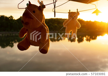 silhouette hanging rhino and bear toy at sunset water lake 57103091