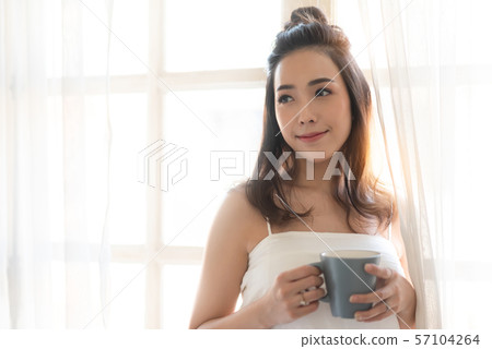 Beautiful Asian woman is holding a cup of coffee. 57104264