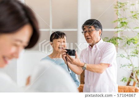 Senior couple taking a picture of their grandchildren with a digital camera 57104867