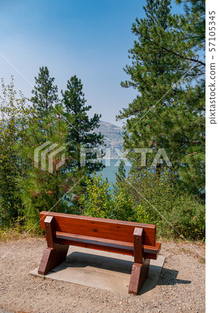Wooden bench in rest area on hike route with beautiful view over a lake. Wooden bench in rest area on hike route with beautiful view over a lake. 57105345