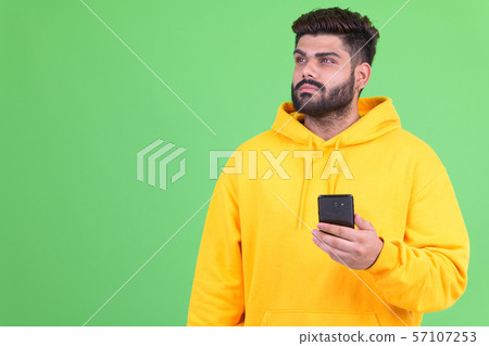 Young overweight bearded Indian man thinking while using phone 57107253