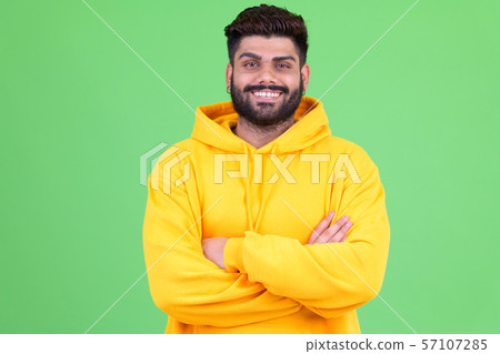 Happy young overweight bearded Indian man smiling with arms crossed 57107285