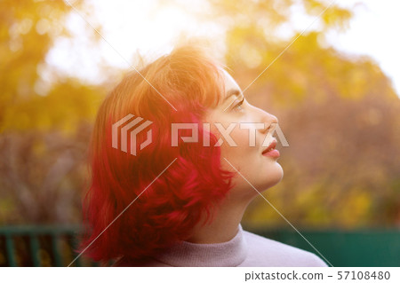 Beautiful woman with red dyed hair and background of autumn yellow leaves.  57108480