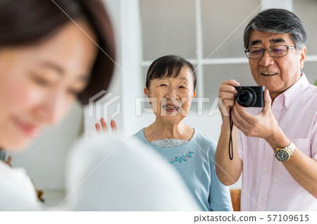 Senior couple taking a picture of their grandchildren with a digital camera 57109615