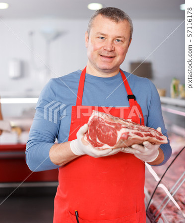 Positive man seller offering meat in shop Positive man seller offering meat in shop 57116178