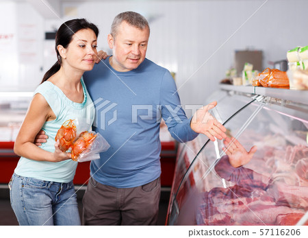 Positive couple customers choosing meat in shop Positive couple customers choosing meat in shop 57116206