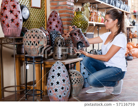 Female buyer chooses ceramic dishes and decorative items in a store 57116759