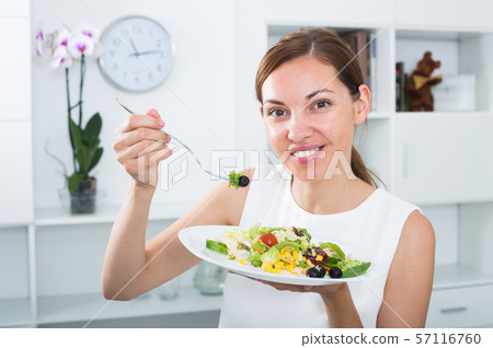 smiling woman eating salad 57116760