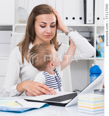Perplexed girl with child is having issue while working behind laptop 57117000