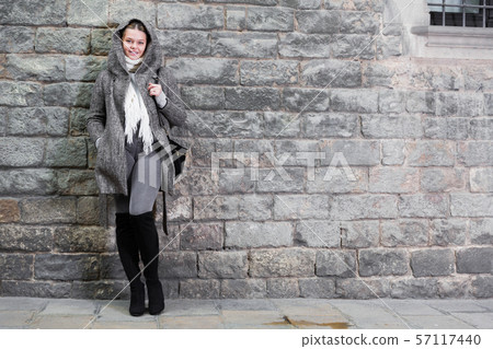cheerful female in coat hood near wall 57117440