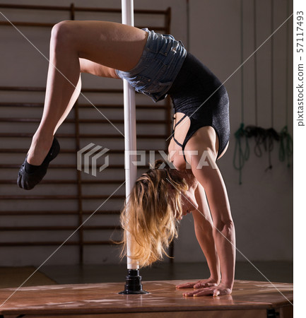 Attractive sports girl dancer engaged on pylon at gym 57117493