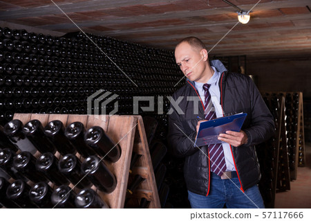Wine producer with clipboard in wine cellar Wine producer with clipboard in wine cellar 57117666