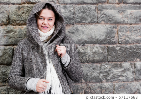 cheerful female in coat hood near wall 57117668